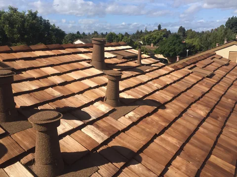 Stone coated vents on a new wood shake roof with hills behind