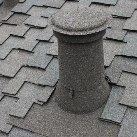 Grey stone coated vent with a cap on grey shingles, close up