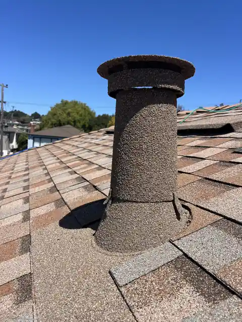 Stone coated vent with a cap on a tan roof