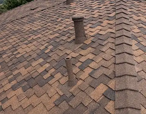Two stone coated pipes on brown architectural shingles