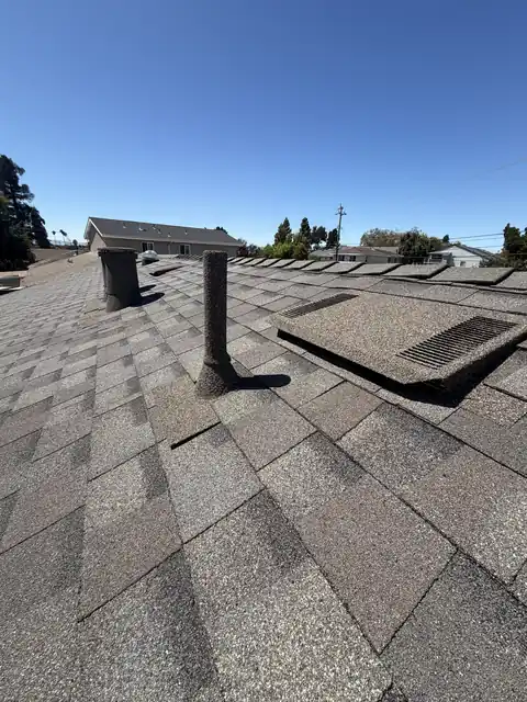 Stone coated pipe and flat vent on a grey roof
