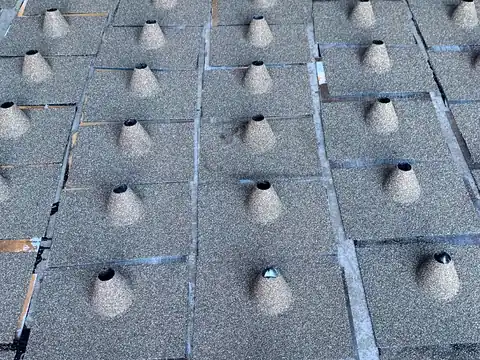 A grid of stone coated cone vents installed across a shingle roof, seen from above
