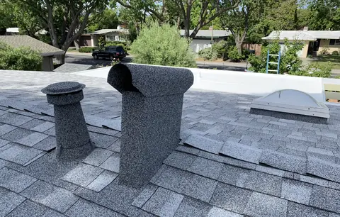 Stone coated dormer vent and pipe on a light grey roof